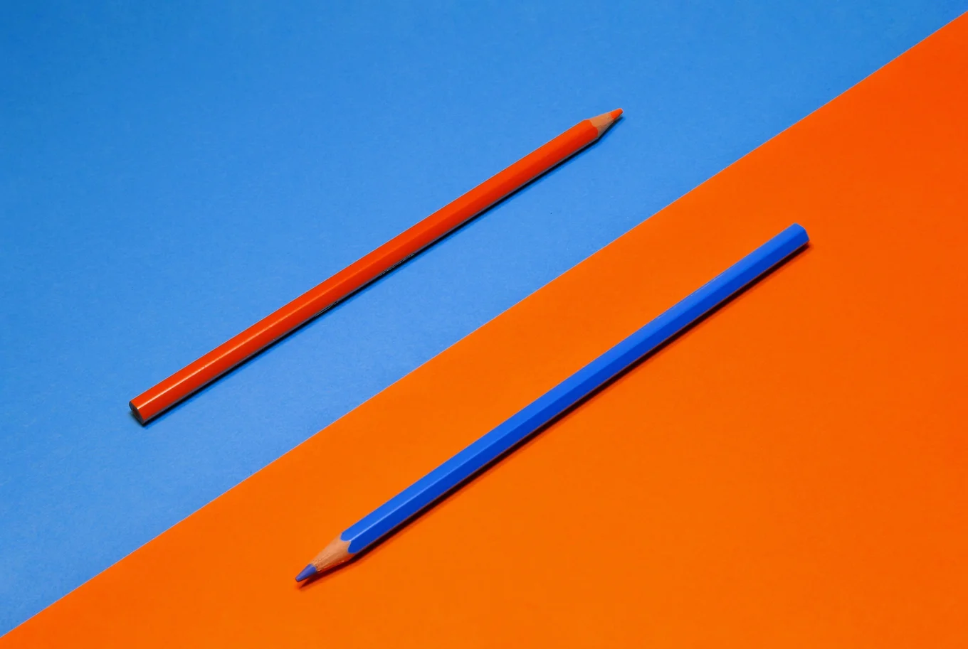Blue and orange pencils on blue and orange paper.