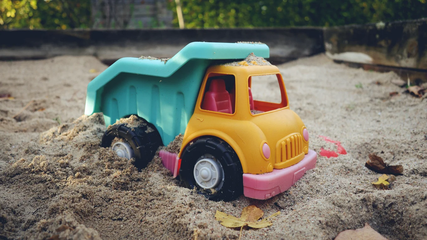 Colourful toy dump truck in sandbox